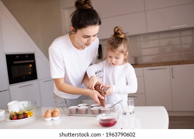 Young Mother Cook Cupcakes With Little Child Daughter 2-3 Year Old At Home Kitchen Close Up. Childhood. Motherhood. 