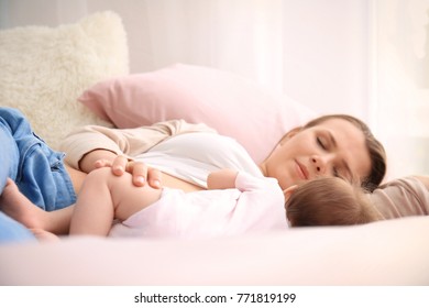 Young mother and cute baby sleeping on bed at home