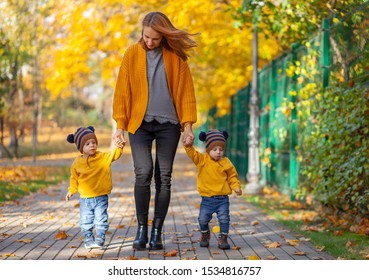 Young Mother With Cute Twins Walking Outdoors