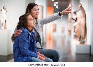 Young Mother And Daughter Exploring Antique Statues In The Museum. Focus On Child 