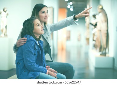 Young Mother And Daughter Exploring Antique Statues In The Museum. Focus On Child