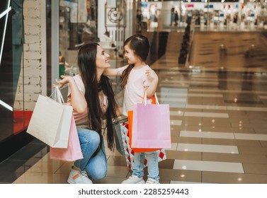 young mother and daughter holding shopping bags, shopping in the mall. Family shopping. - Powered by Shutterstock