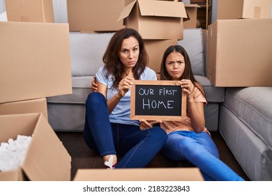 Young Mother And Daughter Sitting On The Floor At New Home Skeptic And Nervous, Frowning Upset Because Of Problem. Negative Person. 