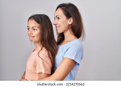 Young Mother And Daughter Standing Over White Background Looking To Side, Relax Profile Pose With Natural Face And Confident Smile. 