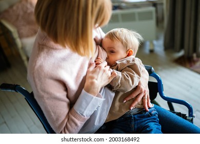 Young Mother With Disability In Wheelchair Breast Feeding Her Child At Home