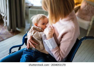 Young Mother With Disability In Wheelchair Breast Feeding Her Child At Home