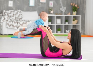 Young Mother Doing Exercises While Holding Baby At Home