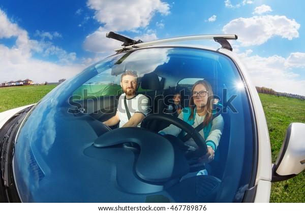 Young mother driving\
car with her family