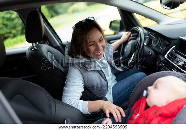 a young mother driving a car looks at a baby\
in a carrier in the front\
seat