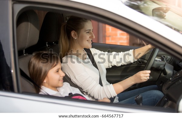 Young mother\
driving car to school with\
daughter