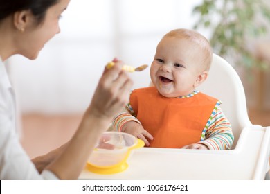 Young mother feeding her baby son with fruit puree - Shutterstock ID 1006176421