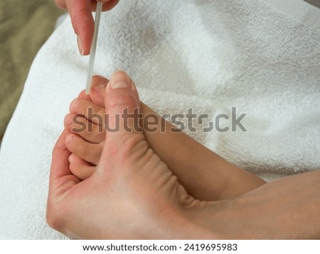 Young mother filling her baby toenails using ceramic file nail. Close up, selective focus, health care concept.