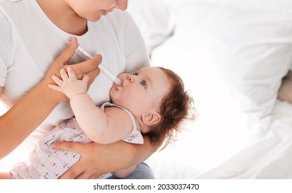 A Young Mother Gives A Sick Child Medicine With The Help Of A Dispenser. The Child Takes Medicine For Teething. Treatment.