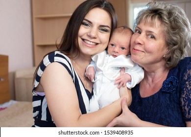 Young mother and grandmother with a baby boy in her arms in a room