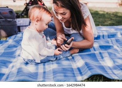 young mother and happy baby using mobile phone outdoors. technology concept - Shutterstock ID 1642984474