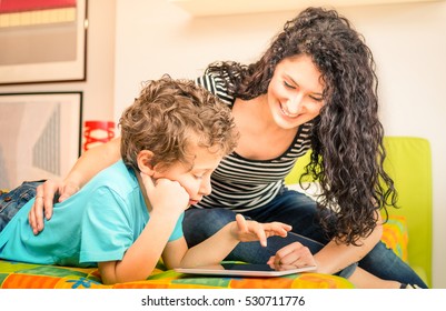 Young Mother Having Fun With Son Using Tablet On Bed - Learning Computer Tech With Sister In Children Room - Teacher Showing Boy How To Interact On Modern Device - Vivid Filter With Focus On Kid Face