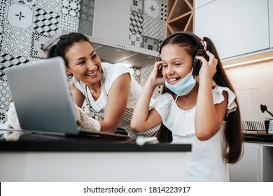 Young Mother Helping Her Daughter On E-learning Session During Covid-19 Pandemic Crisis Lockdown Or Quarantine. Illness Prevention And New Normal Concept.