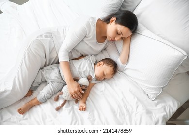 Young Mother And Her Adorable Baby With Toy Sleeping On Bed