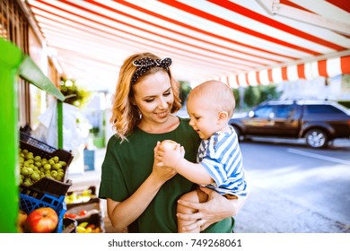 Young Mother With Her Baby Boy At Outdoor Market.