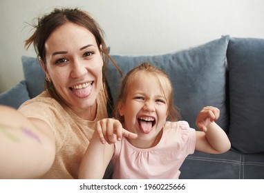 Young Mother With Her Baby Daughter Take Selfies And Fool Around Looking At The Camera