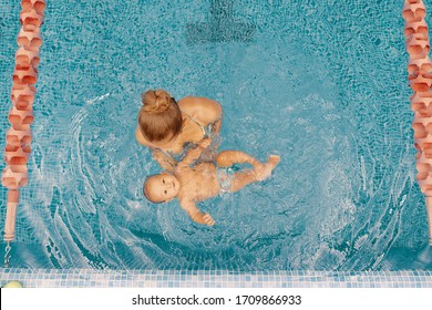 Young mother and her baby enjoying a baby swimming lesson in the pool. Child having fun in water with mom - Powered by Shutterstock