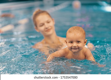 Young Mother And Her Baby Enjoying A Baby Swimming Lesson In The Pool. Child Having Fun In Water With Mom