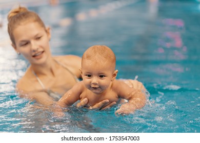 Young Mother And Her Baby Enjoying A Baby Swimming Lesson In The Pool. Child Having Fun In Water With Mom