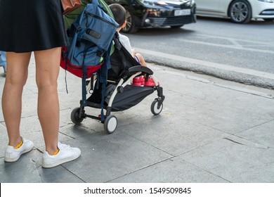 Young Mother With Her Baby Stroller With Busy City Traffic