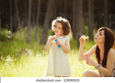 Young mother and her child playing with soap bubbles