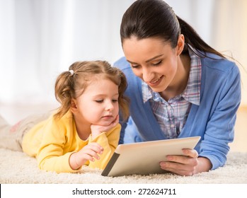 Young mother and her cute daughter are looking at laptop.