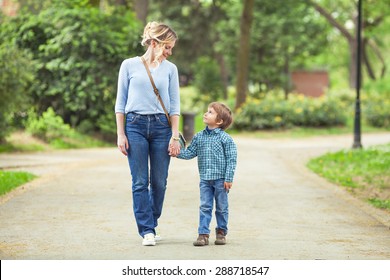 Junge Mutter und ihr süßer kleiner Sohn, der im Park spaziert