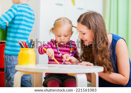 Young mother and her daughter drawing together. Also perfect for kindergarten daycare context.