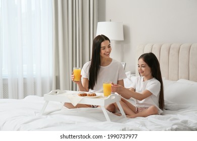 Young mother and her daughter having breakfast on bed at home - Powered by Shutterstock