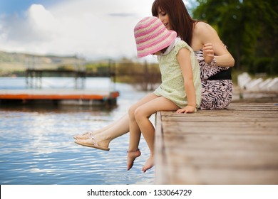 Young mother and her daughter splashing in the lake