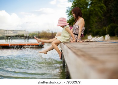 Young Mother And Her Daughter Splashing In The Lake