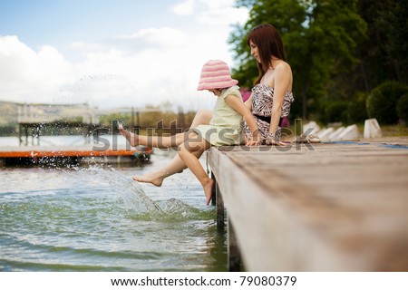 Young mother and her daughter splashing in the lake