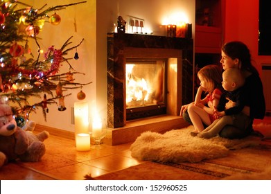 Young mother and her daughters by a fireplace on Christmas - Powered by Shutterstock