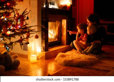 Young mother and her daughters by a fireplace on Christmas - Powered by Shutterstock