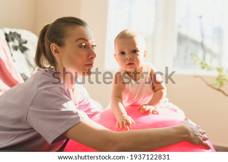Young mother and her happy baby having fun with gymnastic ball. Gymnastics for kids on fitball. High quality photo