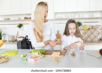 Young Mother And Her Kid Making School Sandwich For Lunch. Preparing For School. Lunch Box With Appetizing Food And School Bag On Kitchen Background.
Schoolgirl And Her Mom At Kitchen.