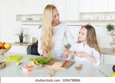 Young Mother And Her Kid Making School Sandwich For Lunch. Preparing For School. Lunch Box With Appetizing Food And School Bag On Kitchen Background.
Schoolgirl And Her Mom At Kitchen.