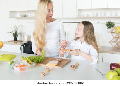 Young Mother And Her Kid Making School Sandwich For Lunch. Preparing For School. Lunch Box With Appetizing Food And School Bag On Kitchen Background.
Schoolgirl And Her Mom At Kitchen.