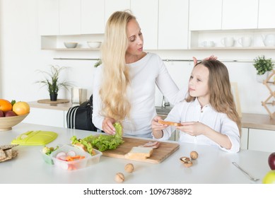 Young Mother And Her Kid Making School Sandwich For Lunch. Preparing For School. Lunch Box With Appetizing Food And School Bag On Kitchen Background.
Schoolgirl And Her Mom At Kitchen.