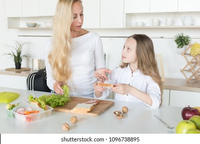 Young Mother And Her Kid Making School Sandwich For Lunch. Preparing For School. Lunch Box With Appetizing Food And School Bag On Kitchen Background.
Schoolgirl And Her Mom At Kitchen.