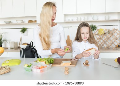 Young Mother And Her Kid Making School Sandwich For Lunch. Preparing For School. Lunch Box With Appetizing Food And School Bag On Kitchen Background.
Schoolgirl And Her Mom At Kitchen.