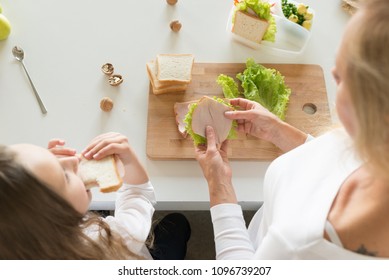 Young Mother And Her Kid Making School Sandwich For Lunch. Preparing For School. Lunch Box With Appetizing Food And School Bag On Kitchen Background.
Schoolgirl And Her Mom At Kitchen.