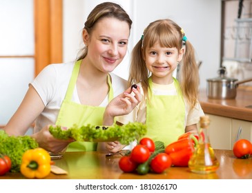 Young Mother And Her Kid Making Vegetable Salad