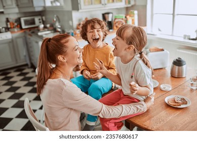 Young mother and her kids having breakfast together and being messy in the kitchen - Powered by Shutterstock