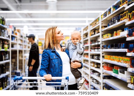 Young mother with her little baby boy at the supermarket.