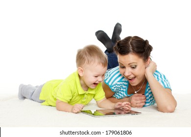 Young Mother And Her Little Son With Computer Tablet Lie On A White Background. Happy Family.